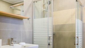 Een moderne badkamer met een glazen douchecabine, een wastafelmeubel met een wastafel en een spiegel erboven.