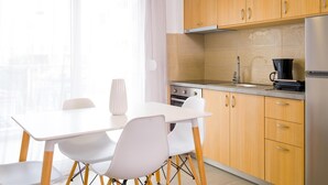 A modern kitchen with wooden cabinets, a stainless steel sink, and a black coffee maker. - Elounda Olithos Apartments 4 (Agios Nikolaos)