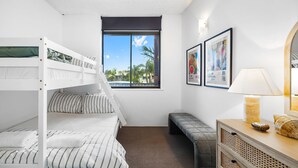 A room with a bunk bed, a bench, a desk with a lamp, and framed artwork on the wall.
