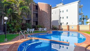 A swimming pool with a brick wall and a white building in the background.