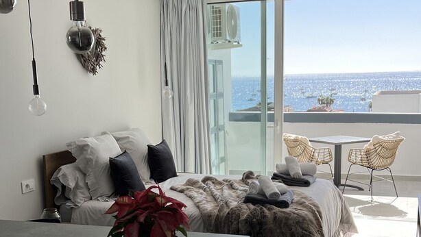 Ein modernes Schlafzimmer mit Bett, Nachttisch und Meerblick.