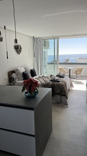 Ein modernes Schlafzimmer mit Bett, Nachttisch und Meerblick.