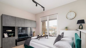 Une chambre moderne avec un lit, une télévision et une vue sur le balcon.