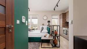 Un appartement moderne comprenant un lit, un bureau, une lampe, une horloge et une cuisine.