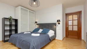 A bedroom with a bed, a wardrobe, a door, and a hanging light fixture.