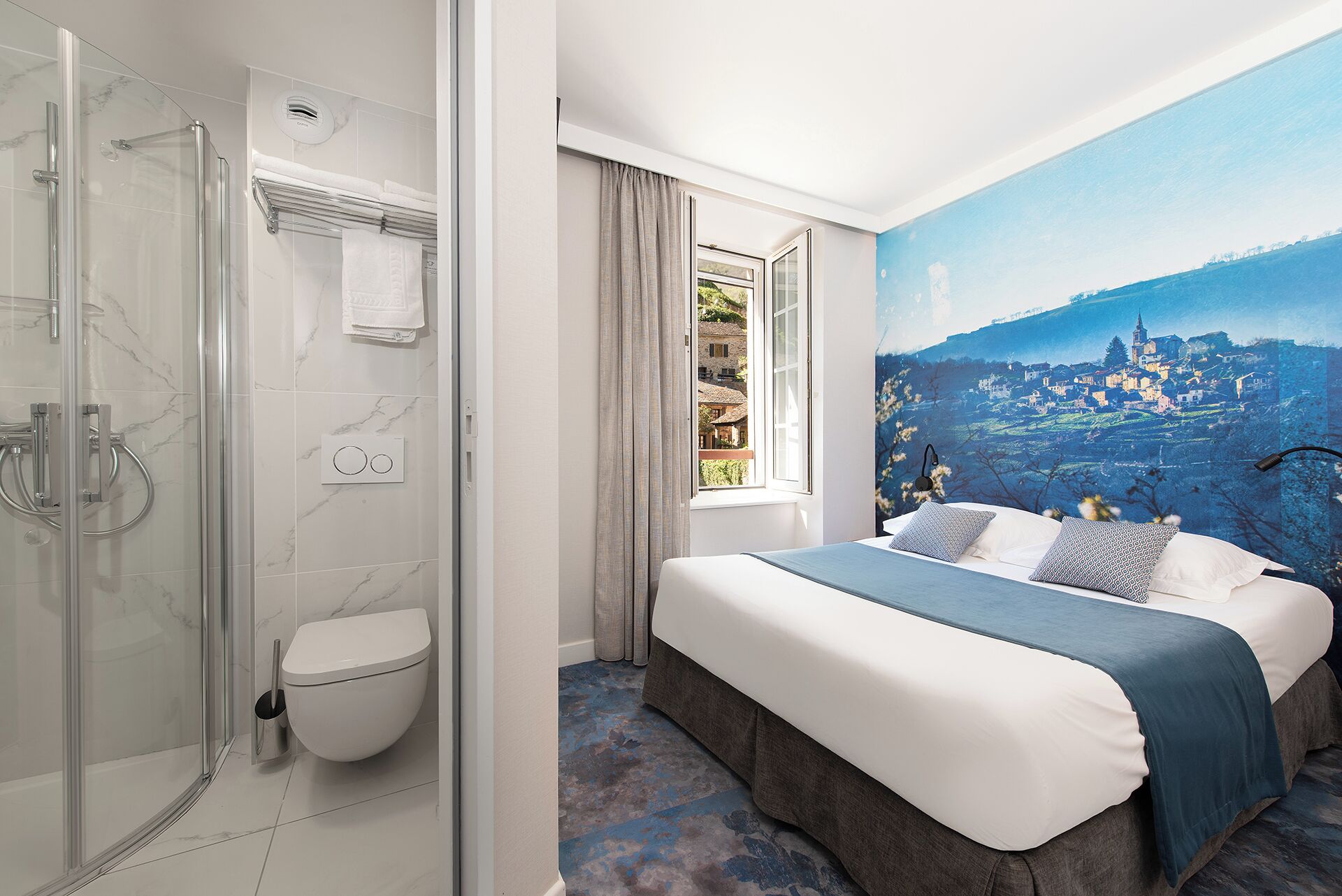 Habitación de hotel con ducha, inodoro y cama con un mural de un paisaje urbano en la pared.