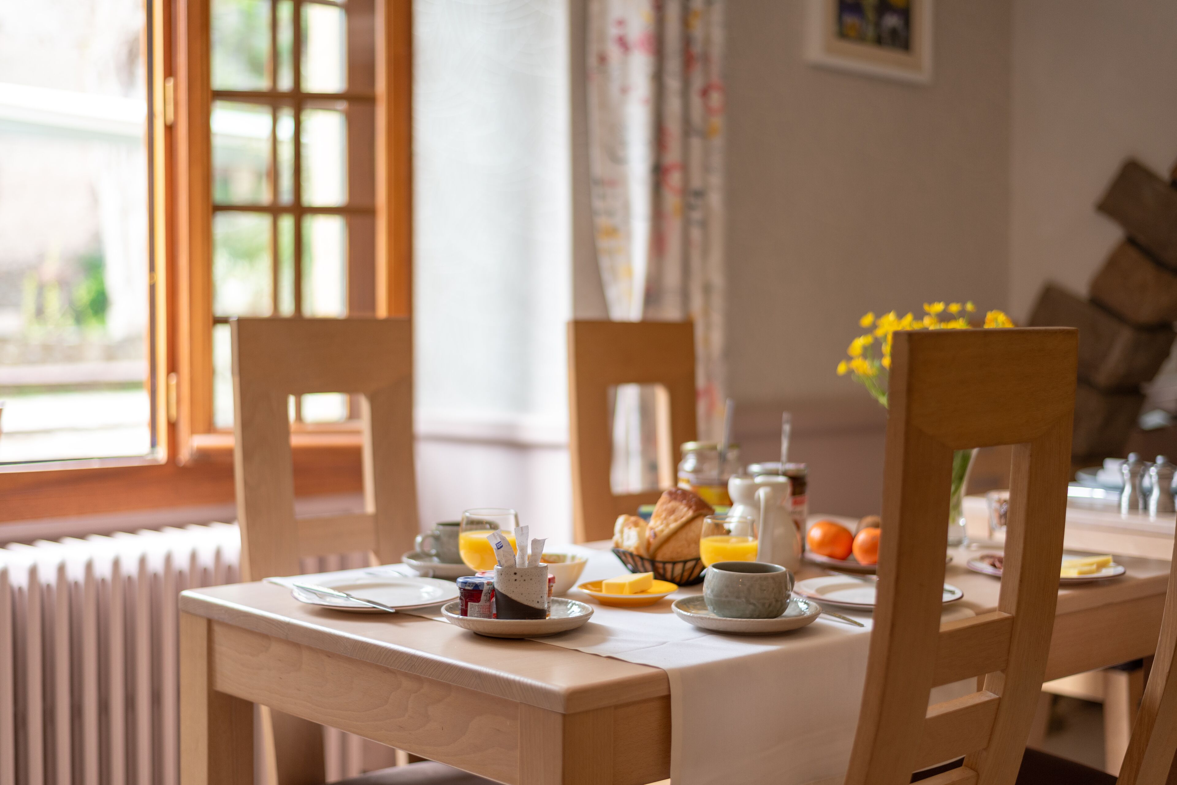 A breakfast table set with plates, cups, and a fruit basket.