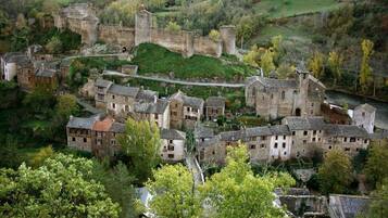 A historic village with stone buildings, a castle, and a river.