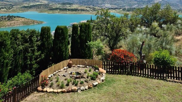 A mountainous landscape with a lake and a fenced garden area. - Stunning Villa with a Private Pool, Panoramic views of Lake Vinuela (Los Romanes)