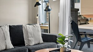 Ein modernes Wohnzimmer mit einem dunkelgrauen Sofa, einem runden Couchtisch und einer Topfpflanze.