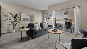 Ein modernes Wohnzimmer mit einem dunkelgrauen Sofa, einem kleinen runden Tisch und einer Topfpflanze.