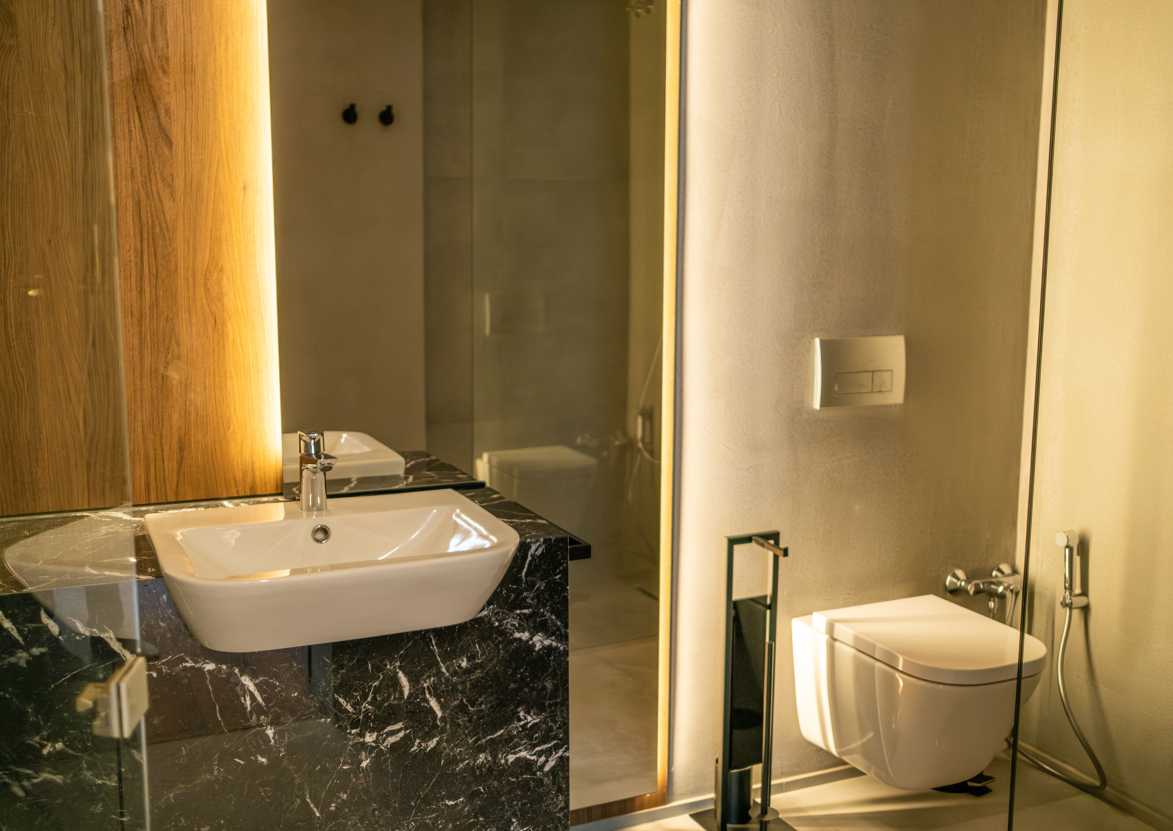 Un baño moderno con lavamanos de mármol, cabina de ducha con paredes de vidrio y inodoro blanco.