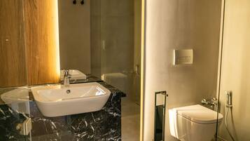 Un baño moderno con lavamanos de mármol, cabina de ducha con paredes de vidrio y inodoro blanco.