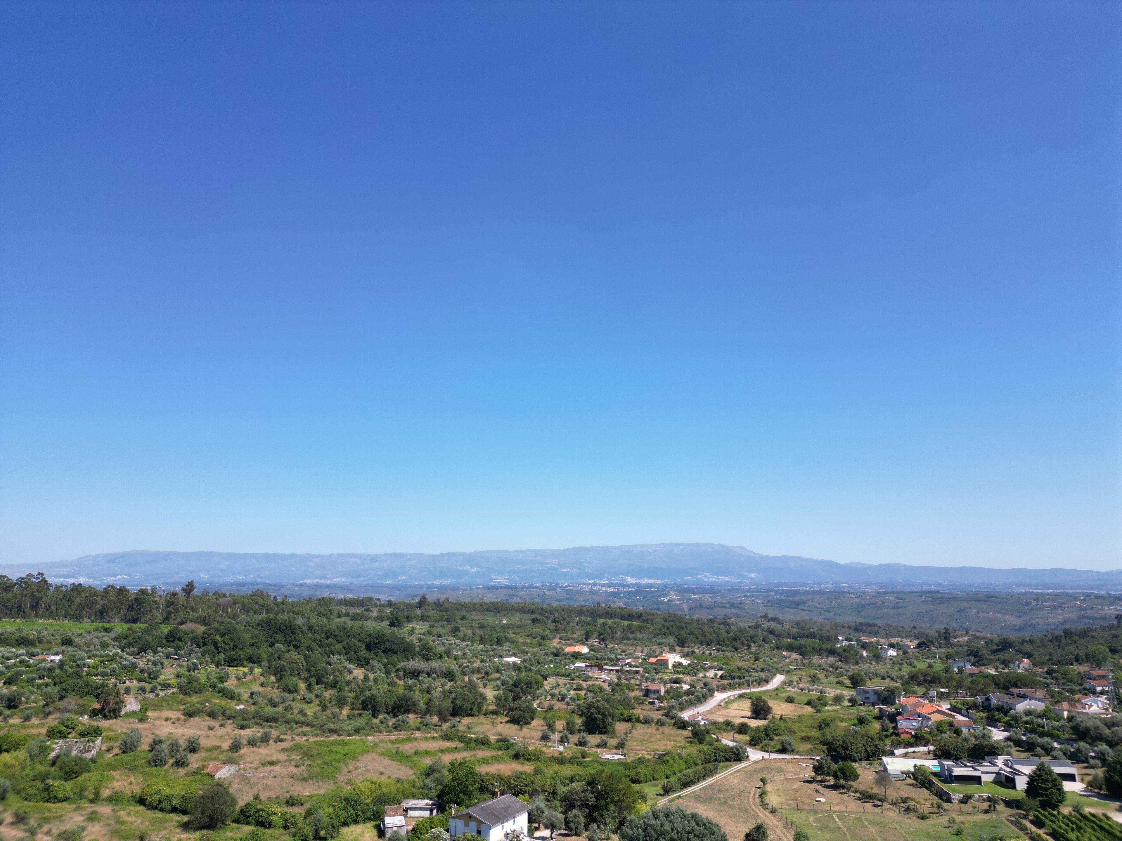 Ländliche Landschaft mit verstreuten Häusern und blauem Himmel.