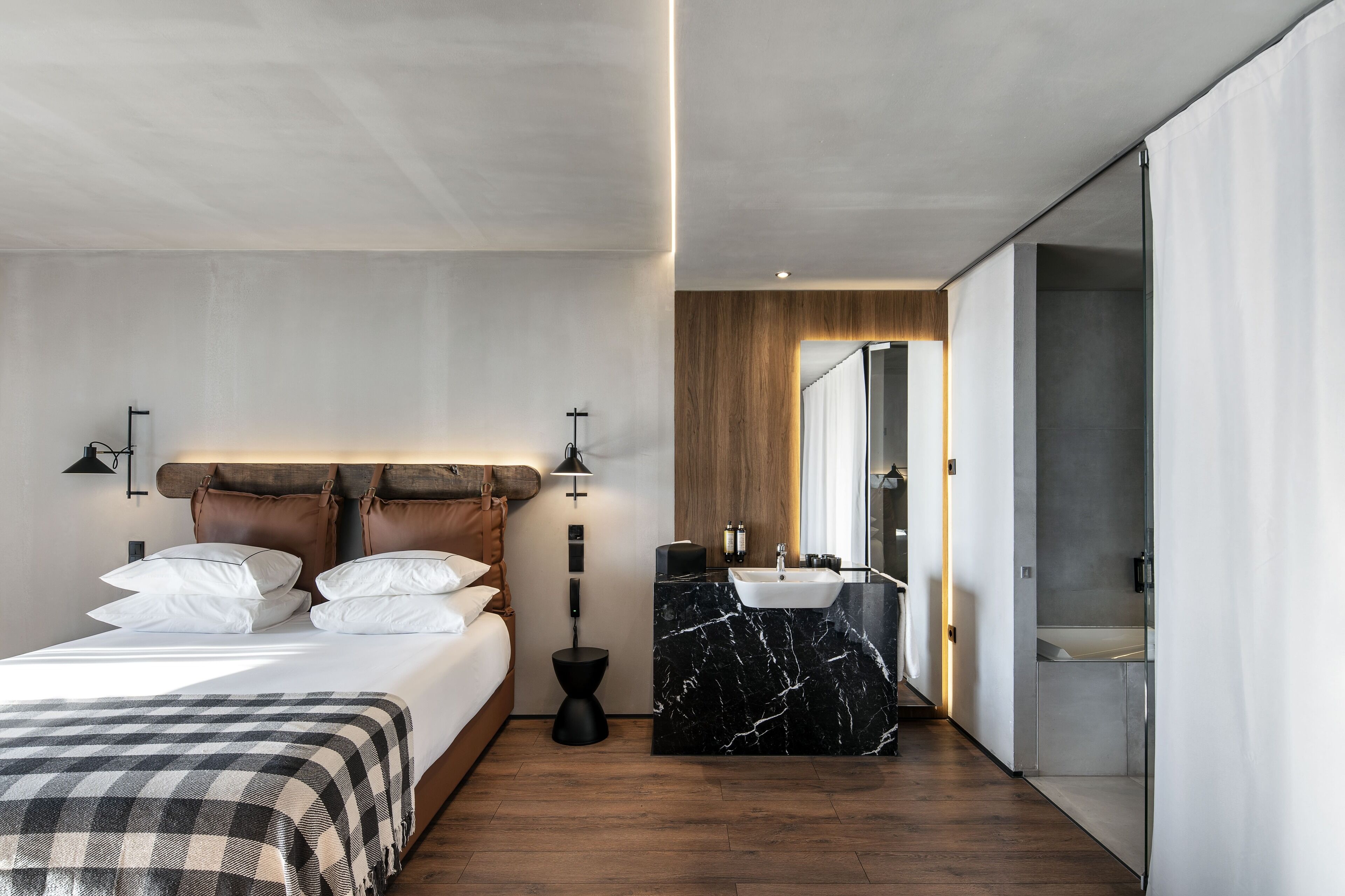 Une chambre moderne comprenant un lit, des tables de chevet, une salle de bain avec un lavabo et un miroir, et un dressing.