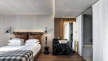 Une chambre moderne comprenant un lit, des tables de chevet, une salle de bain avec un lavabo et un miroir, et un dressing.