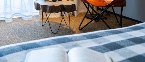 Ein Hotelzimmer mit einem Bett, einem Lesesessel, einem kleinen Tisch mit Pflanze und einer Lampe.