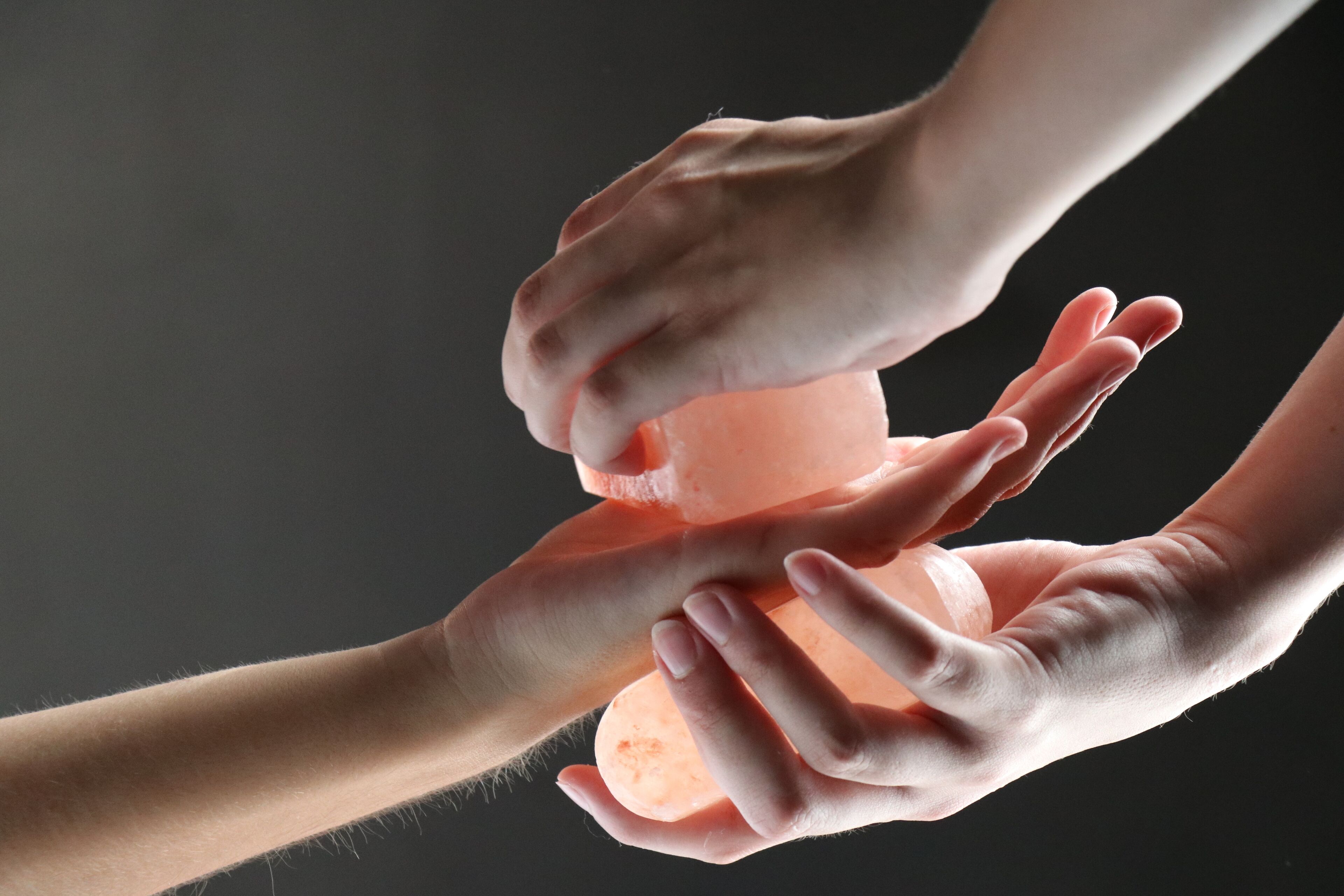 Hands squeezing a translucent orange object, possibly a soap or lotion bottle.