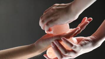 Hands squeezing a translucent orange object, possibly a soap or lotion bottle.