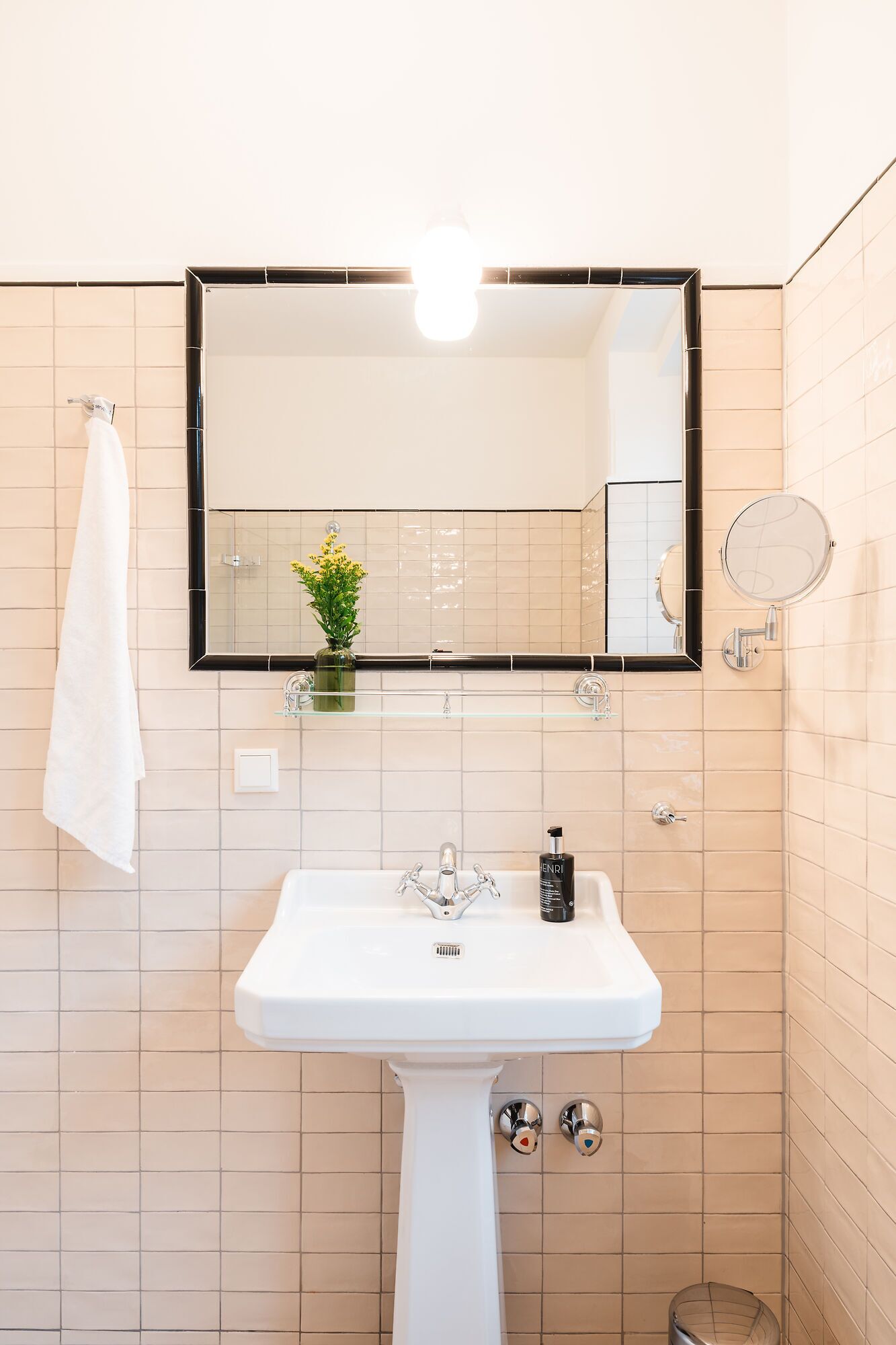 Un baño con lavamanos blanco, un espejo y una toalla colgada en la pared.