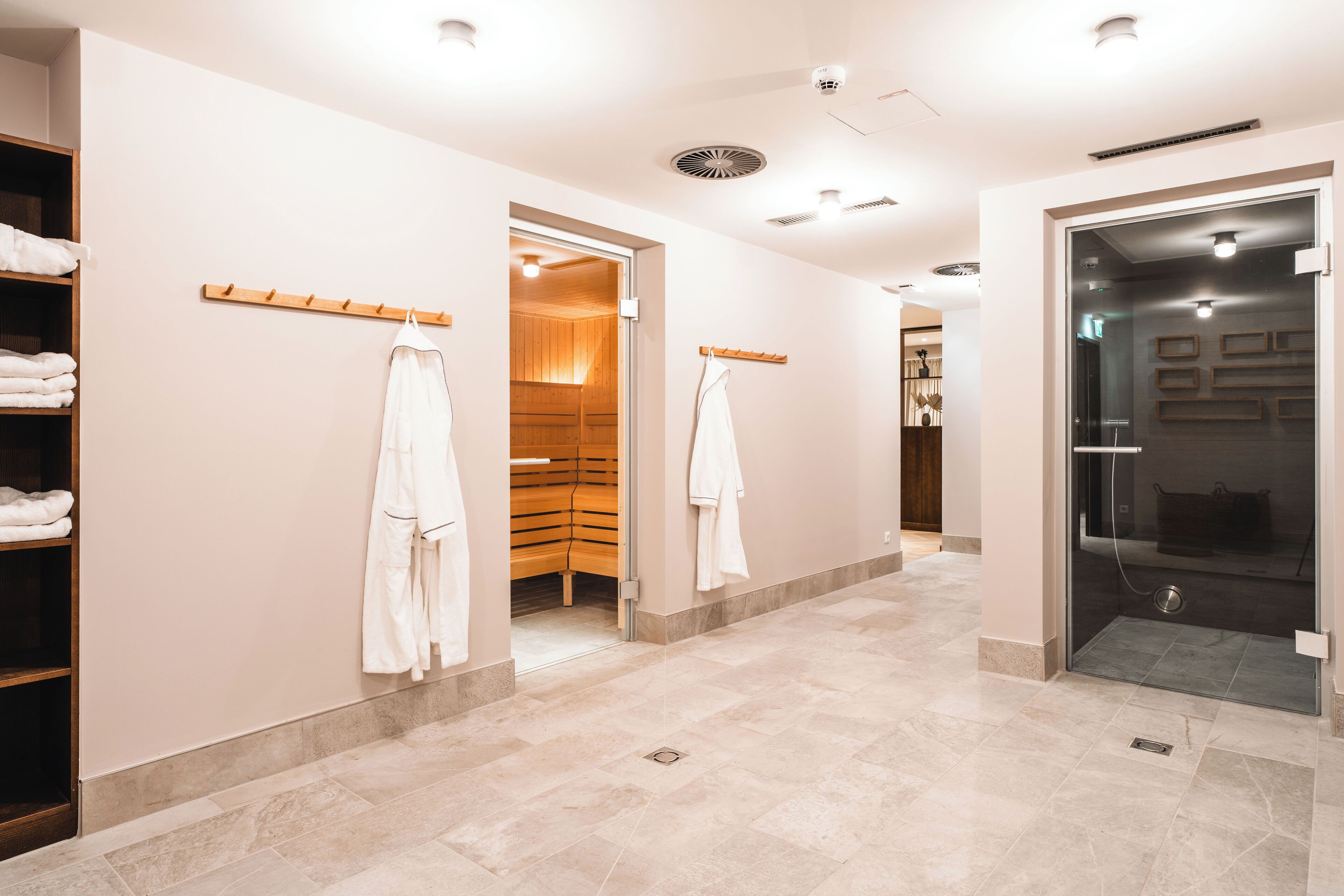 A modern bathroom with a walk-in shower, a glass door, and a wooden bench.