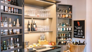 A bar area with shelves of bottles and glasses, a chalkboard menu, and a wooden bucket with bottles.