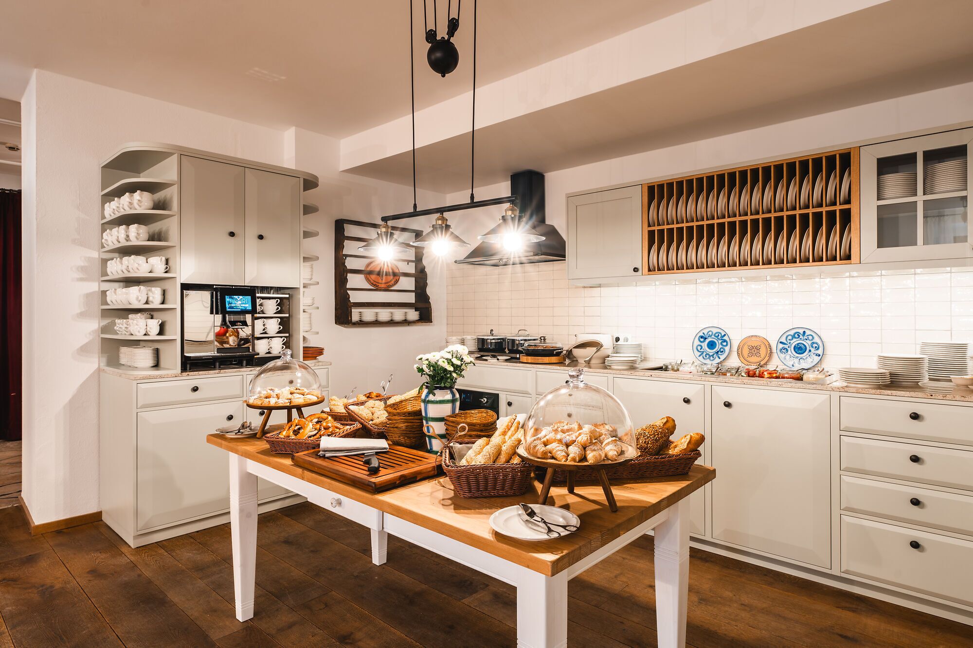 Una cocina con armarios blancos, una mesa de madera con alimentos y un salpicadero de azulejos.