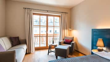 Una habitación de hotel con sofá, sillón, mesita y cama.