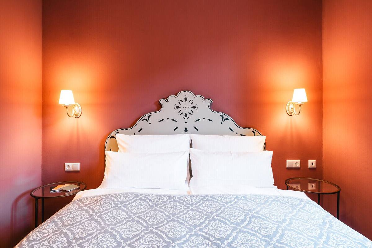 A hotel room with a large bed, two bedside lamps, and a patterned bedspread.
