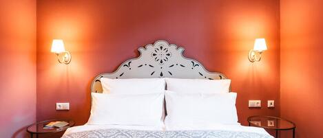 A hotel room with a large bed, two bedside lamps, and a patterned bedspread.