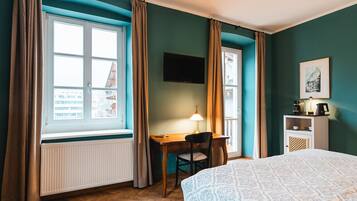 Ein Hotelzimmer mit einem Bett, einem Schreibtisch mit Stuhl, einem Fernseher und einer Heizung.