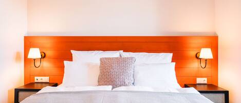 A hotel room with a bed, two bedside lamps, a nightstand, and a power outlet.