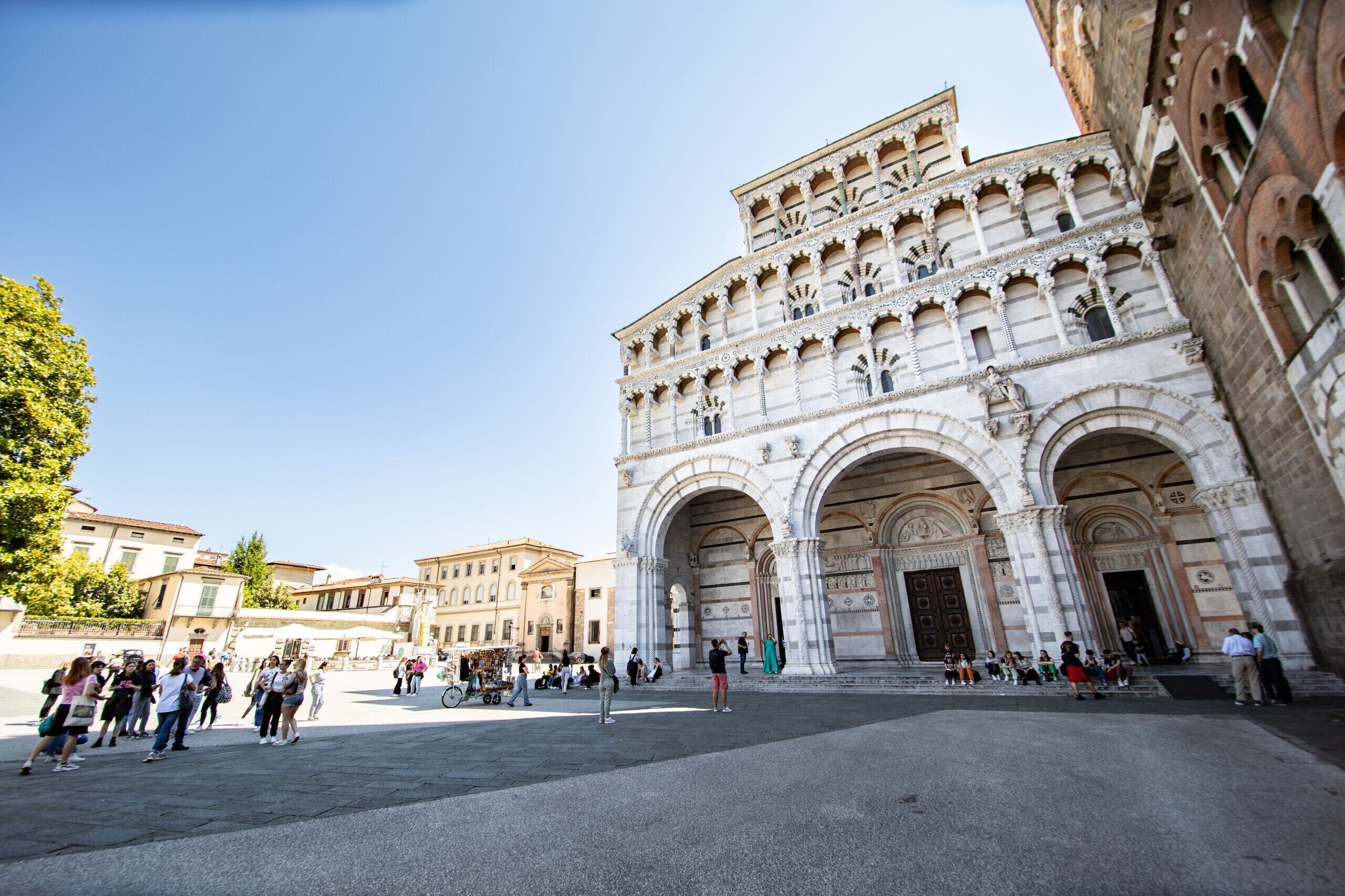 A historic building with ornate architecture, large arched entrances, and a spacious plaza.