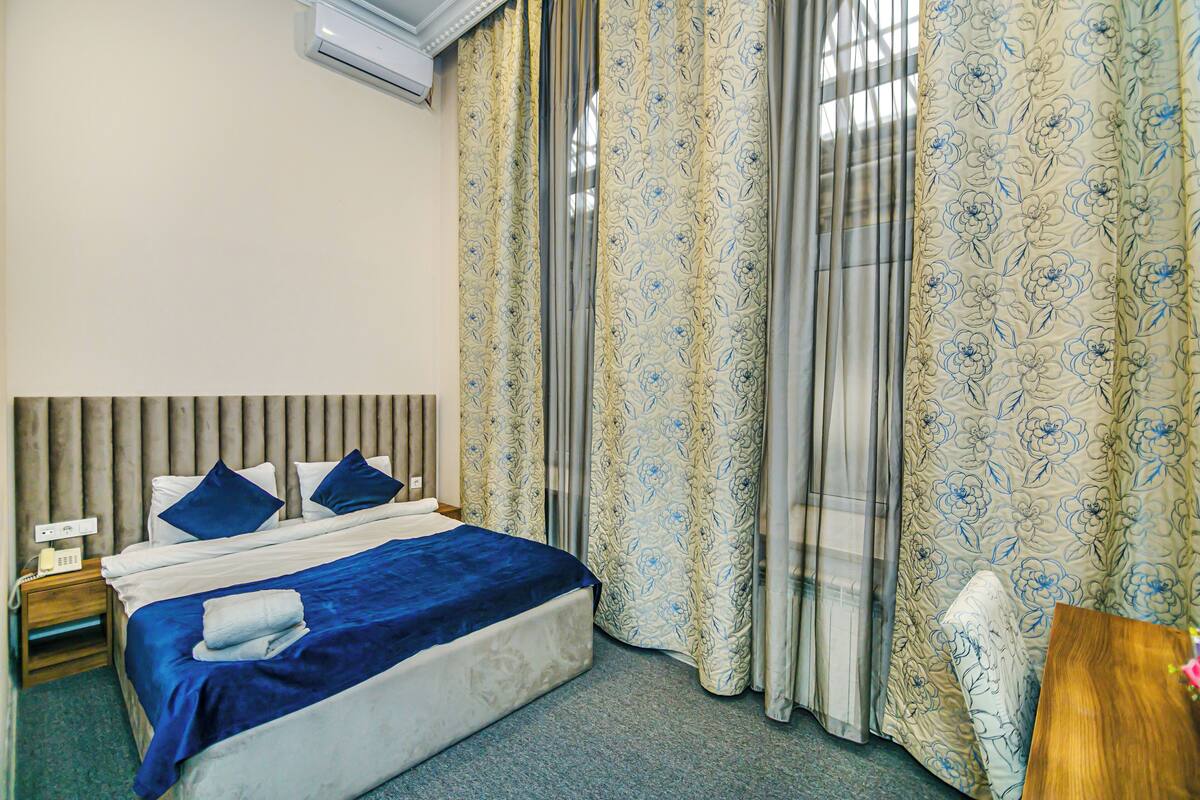 Une chambre d’hôtel avec un lit, des rideaux et une table de chevet.
