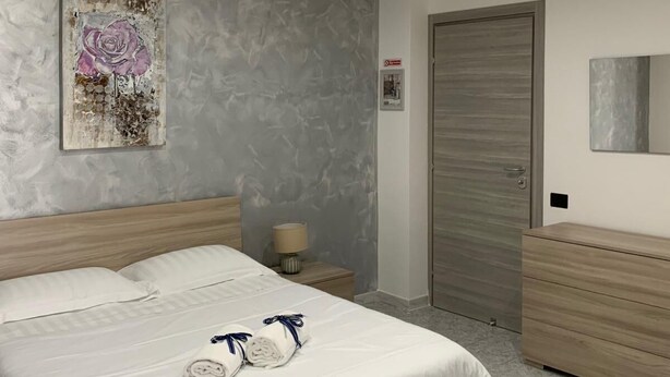 Ein modernes Schlafzimmer mit einem großen Bett, einem Nachttisch, einer Kommode und einer Tür.