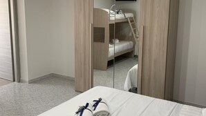 Ein modernes Hotelzimmer mit Etagenbett, großem Spiegel und ordentlich gefalteten Handtüchern auf dem Bett.