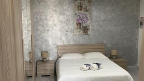 Ein Schlafzimmer mit einem Bett, zwei Nachttischen, einem Spiegel und einem Wandbild.