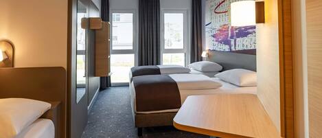 A hotel room with a bed, a desk, a chair, a TV, and a window.