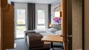 A hotel room with two beds, a small table, and a seating area.