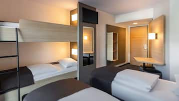 Una habitación de hotel con literas, una mesita de noche con lámpara, un espejo y un estante en la pared.