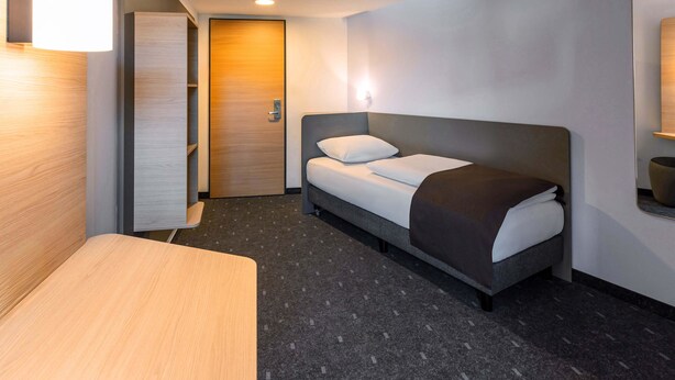 Una habitación de hotel moderna con cama, escritorio y puerta.