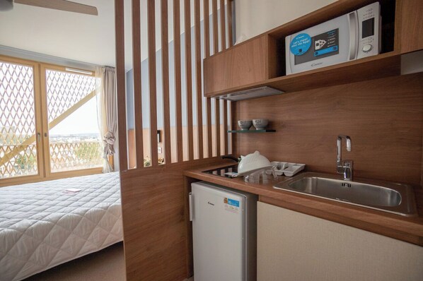 A compact kitchenette with a microwave, a small refrigerator, and a sink.