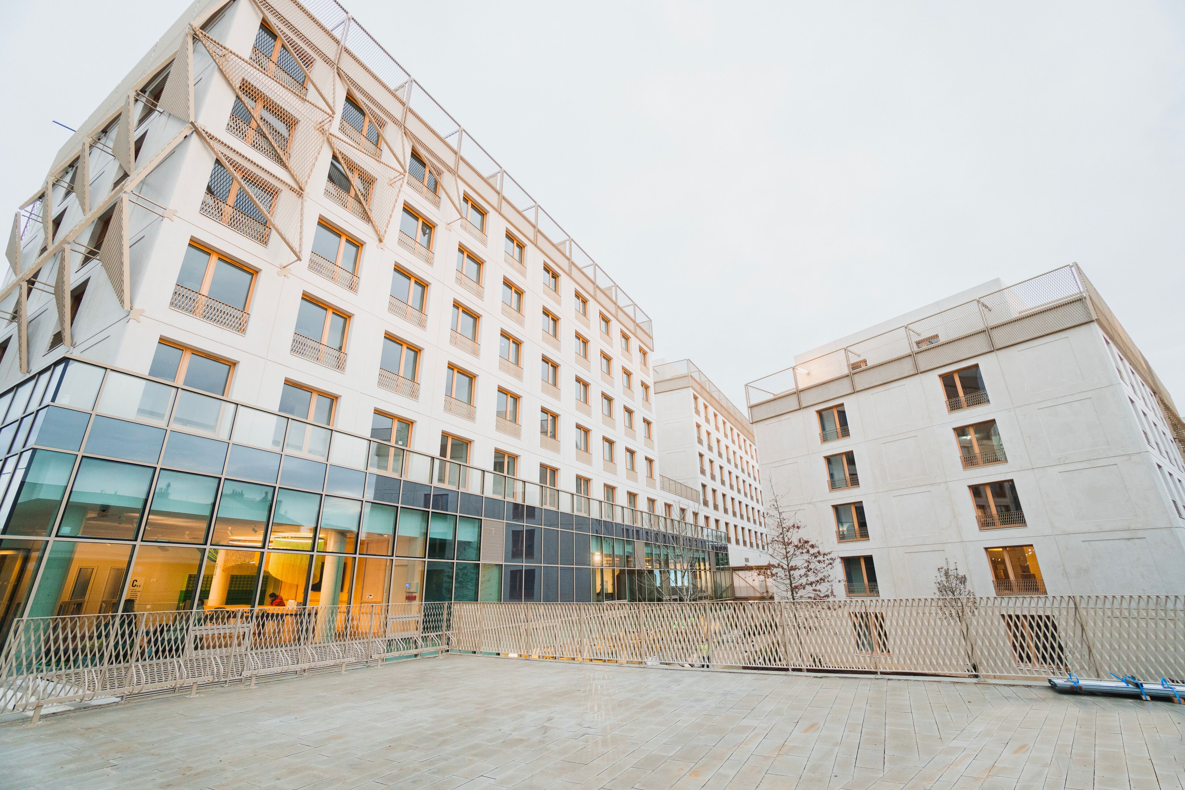 A modern building with a glass facade, multiple floors, and a courtyard area.