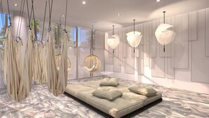 Un dormitorio moderno con una cama grande, sillas colgantes y lámparas colgantes.