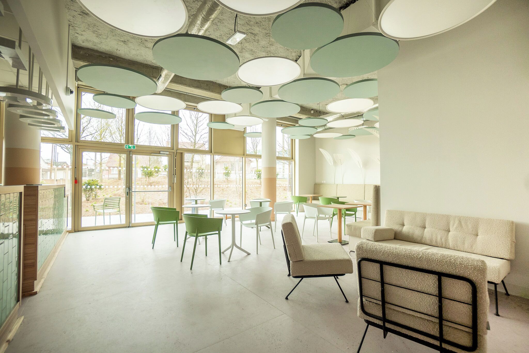 A modern interior with round ceiling lights, a sofa, and tables with chairs.