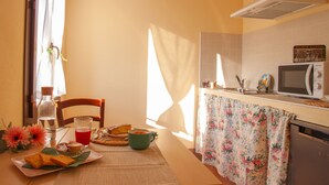 Una cocina con microondas, un lavamanos y una mesa lista para el desayuno.
