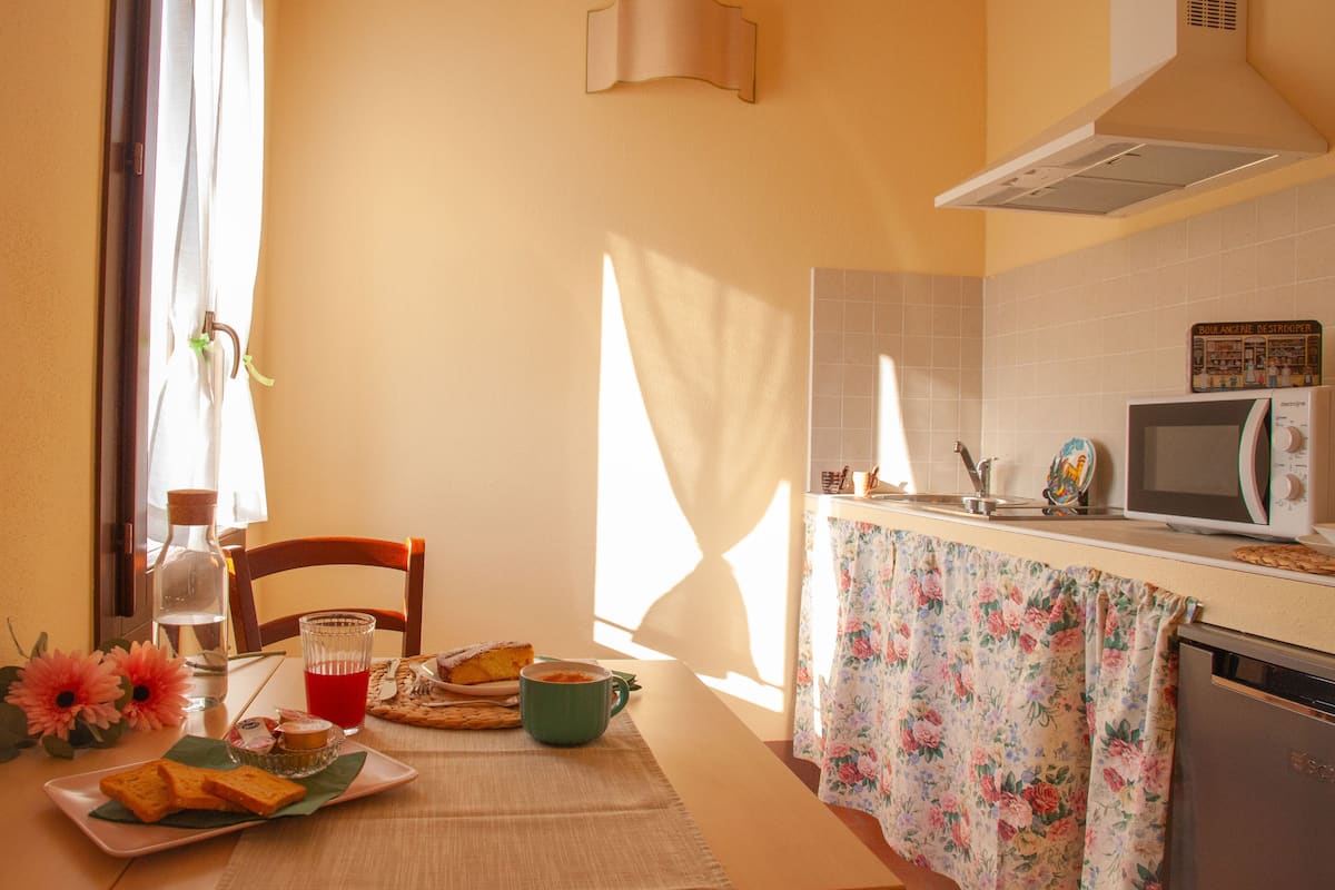 A kitchen with a microwave, a sink, and a table set with breakfast items.