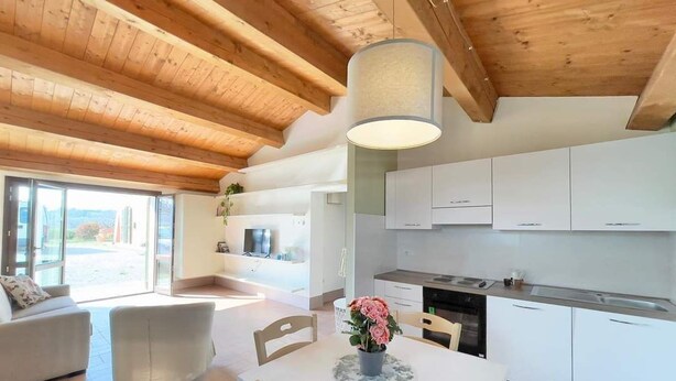 Una cocina moderna con armarios blancos, una mesa de comedor con sillas y una lámpara colgante.