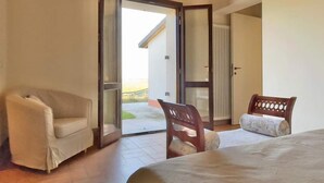 Un dormitorio con cama, dos sillas y una puerta corrediza de vidrio que da a un balcón.