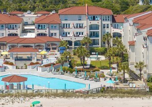 A hotel with multiple buildings, a swimming pool, and palm trees.